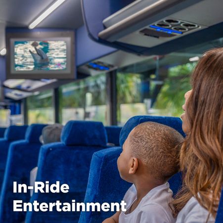 A mother and her small son watch in-ride video about dolphins aboard Mears Connect Orlando Airport Shuttle bus